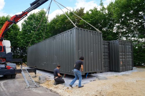 Déchargement d'un container 40 pieds maritime gris sur plateforme en béton - GOLIAT